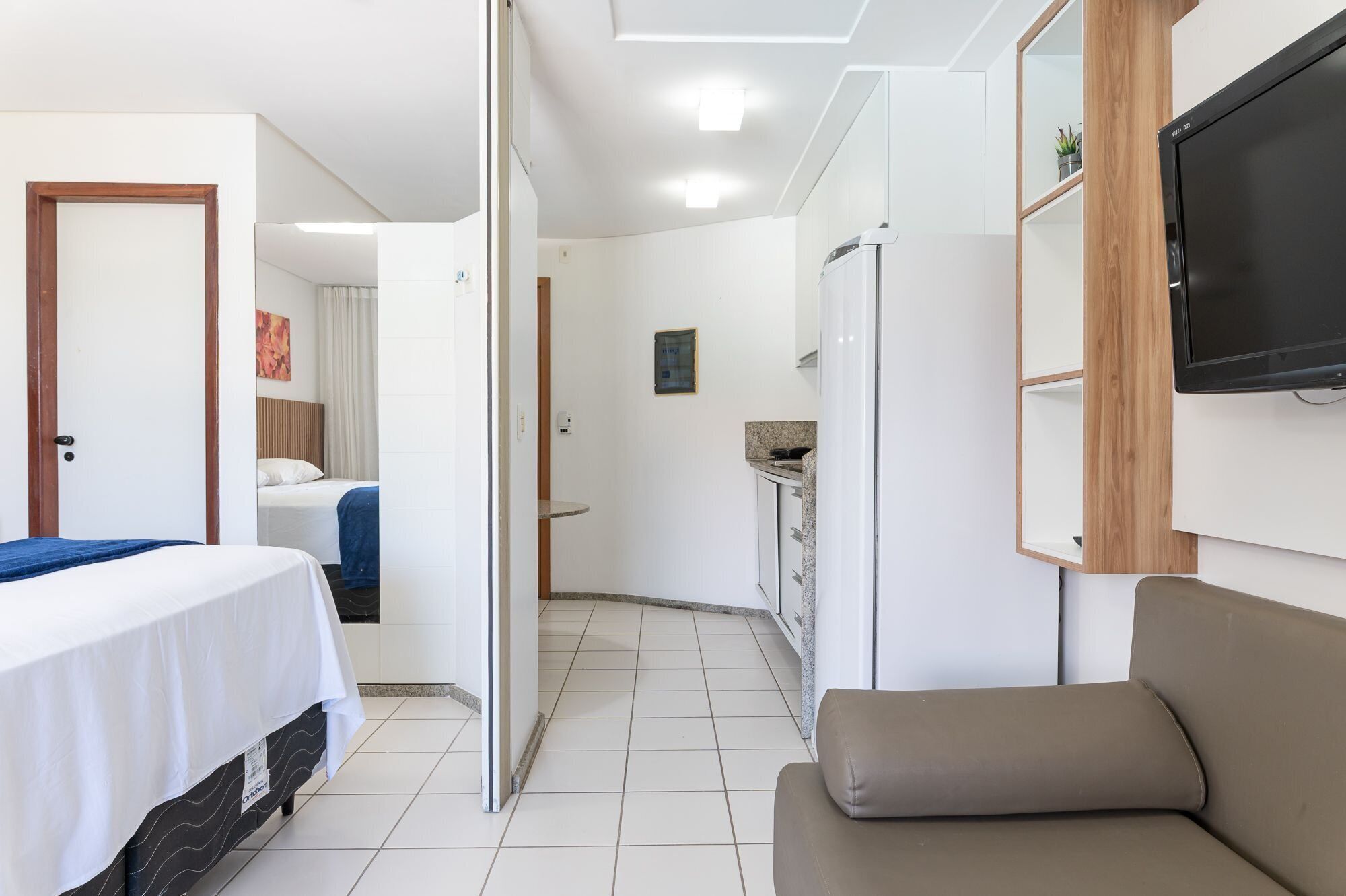 Habitación de hotel con cama, sofá, televisión y kitchenette.