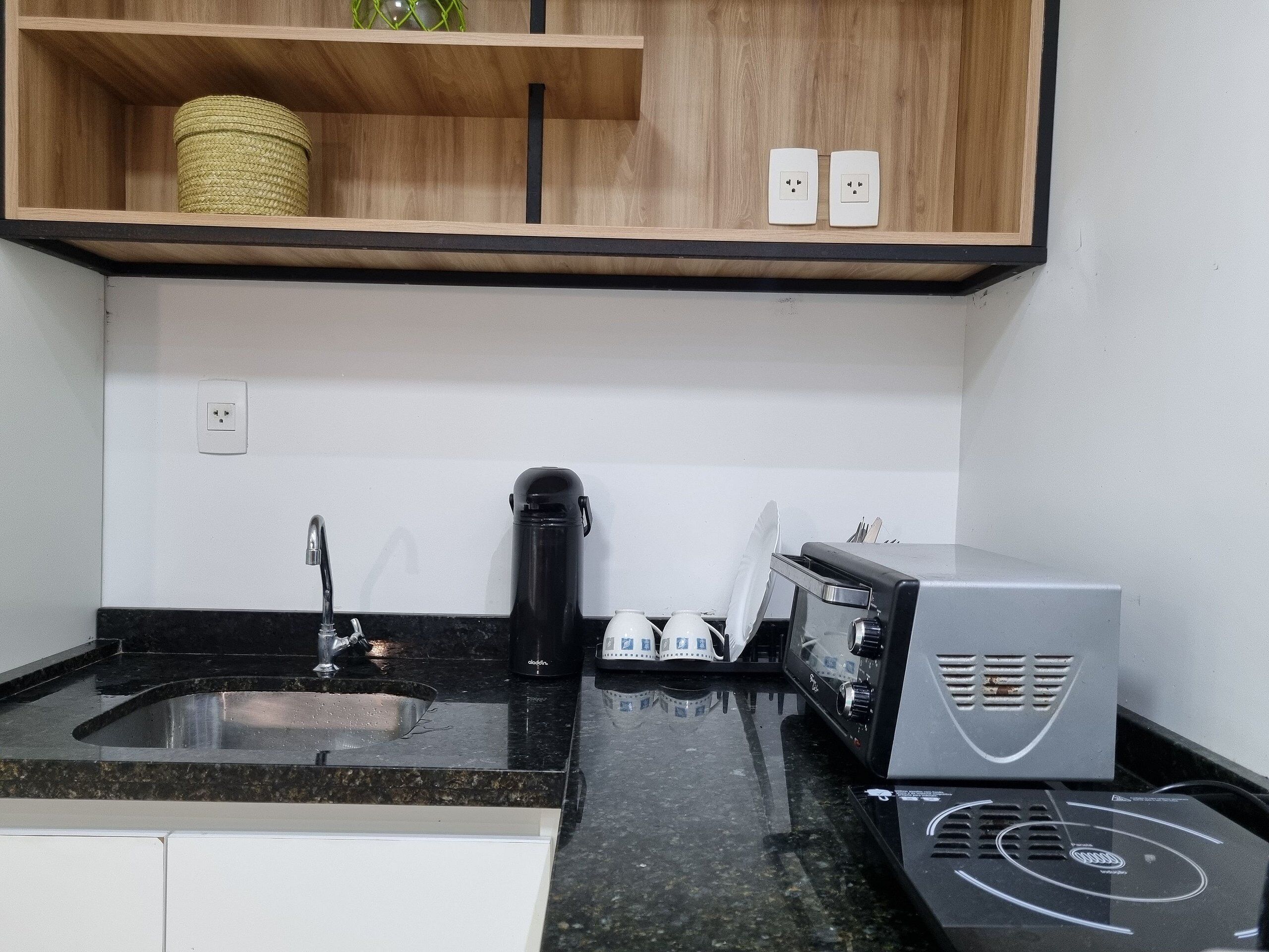 Una cocina con encimera de granito, cafetera, tostadora y microondas.