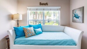 A bedroom with a white bed, a window with a view of greenery, a lamp, and a painting of a turtle. - ~Hot Tub~2 King Beds~3 Bedrooms~Walk to Beach, Free Parking, Close to Downtown (St. Augustine)