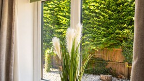 A window with a view of a garden and a wooden fence. - Lodge 3 - Lytton Tree Lodge (Reydon)