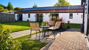 A patio with two wicker chairs, a table, and a glass of wine. - Lodge 3 - Lytton Tree Lodge (Reydon)