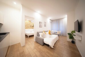 A modern hotel room with a bed, a sofa, a dining area, and a TV. - IV HOUSE 
Luxurious apartment in Rome (Roma)