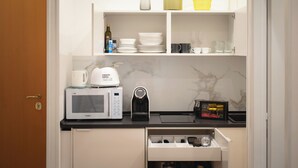 A compact kitchen with a microwave, coffee maker, and storage cabinets. - IV HOUSE 
Luxurious apartment in Rome (Roma)