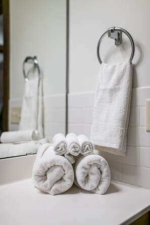 A bathroom with white tiles, a towel rack, and two rolled towels on the counter. - Mynte House l Modern 4BR Near Mayo, Fast WiFi, Parking, Office, Bidet (Rochester)