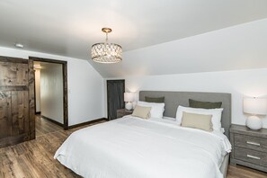 A bedroom with a large bed, two bedside tables with lamps, a wooden wardrobe, and a chandelier. - Mynte House l Modern 4BR Near Mayo, Fast WiFi, Parking, Office, Bidet (Rochester)