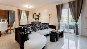 A modern living room with a sofa, a dining table, and a kitchen area. - Angels Villa in Kremasti Near the Beach (Rhodes)