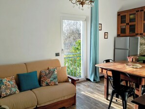 En hyggelig stue med sofa, spisebord og et køkkenområde med skabe og et køleskab.