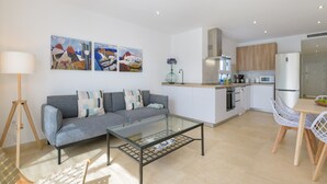 A modern kitchen with white cabinets, a microwave, and a refrigerator. There is a dining area with a table and chairs. - Casa Anzuelo, with Balcony Puerto del Carmen (Puerto del Carmen)