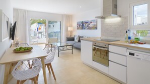 A modern kitchen with white cabinets, a wooden countertop, and a built-in oven. There is a dining area with a table and chairs, and a large window providing a view of the outside. - Casa Anzuelo, with Balcony Puerto del Carmen (Puerto del Carmen)