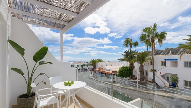 A balcony with a potted plant, white chairs, and a table. - Casa Anzuelo, with Balcony Puerto del Carmen (Puerto del Carmen)