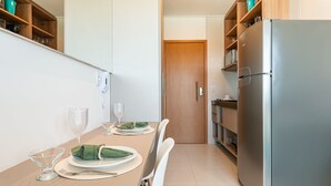Une cuisine moderne avec une table à manger pour deux personnes, un réfrigérateur et des armoires en bois.