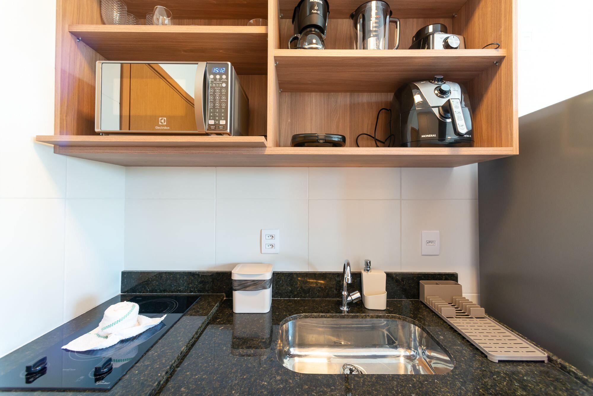 Una cocina con microondas, cafetera y jarra para café sobre la encimera.