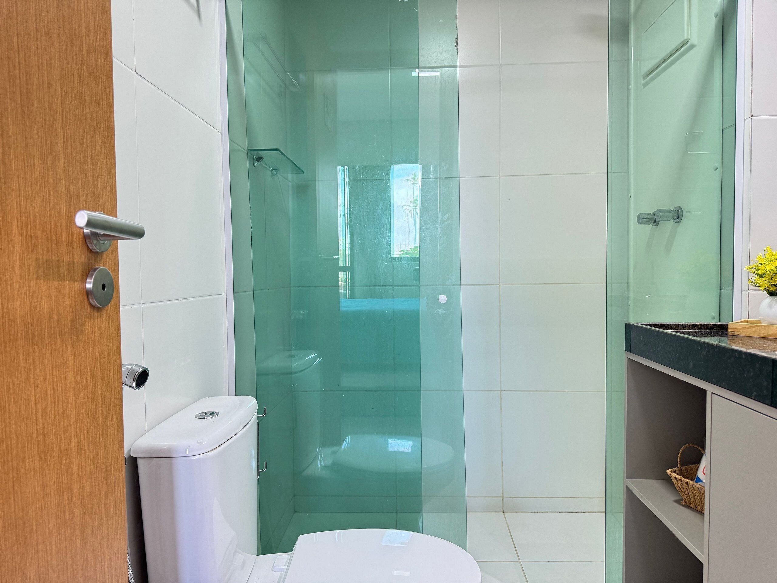 Un baño con cabina de ducha de vidrio, inodoro y lavabo con encimera.