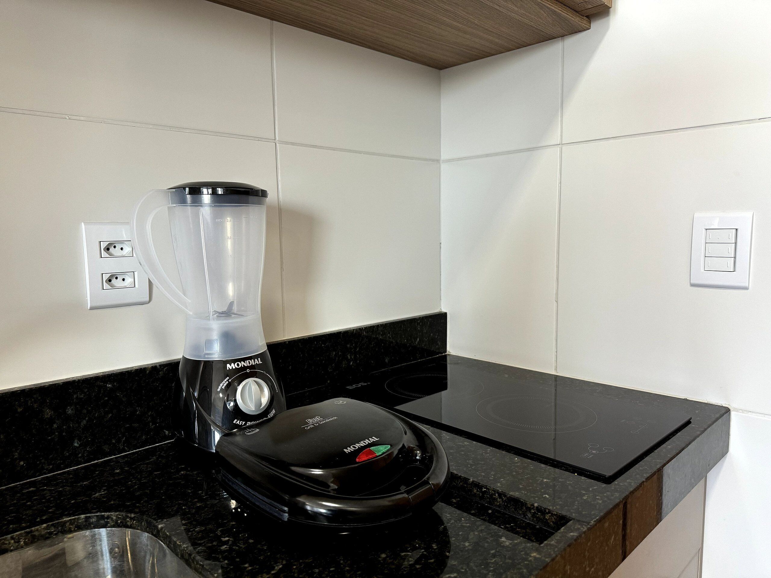 A kitchen with a black countertop, a blender, and a stove.