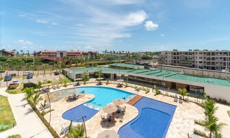 Un resort con una amplia piscina, mobiliario exterior y vistas de edificios circundantes.