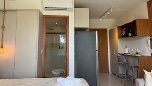 Une chambre d’hôtel moderne comprenant un lit, une salle de bain, une kitchenette et un coin salon.