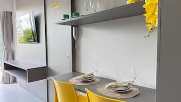 Un comedor moderno con una mesa gris, sillas amarillas y un televisor de pantalla plana montado.