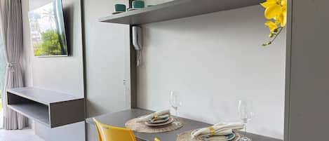 Un comedor moderno con una mesa gris, sillas amarillas y un televisor de pantalla plana montado.