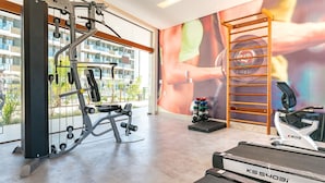 Une salle de sport équipée d’un tapis de course, d’un banc de musculation et d’autres appareils d’exercice.