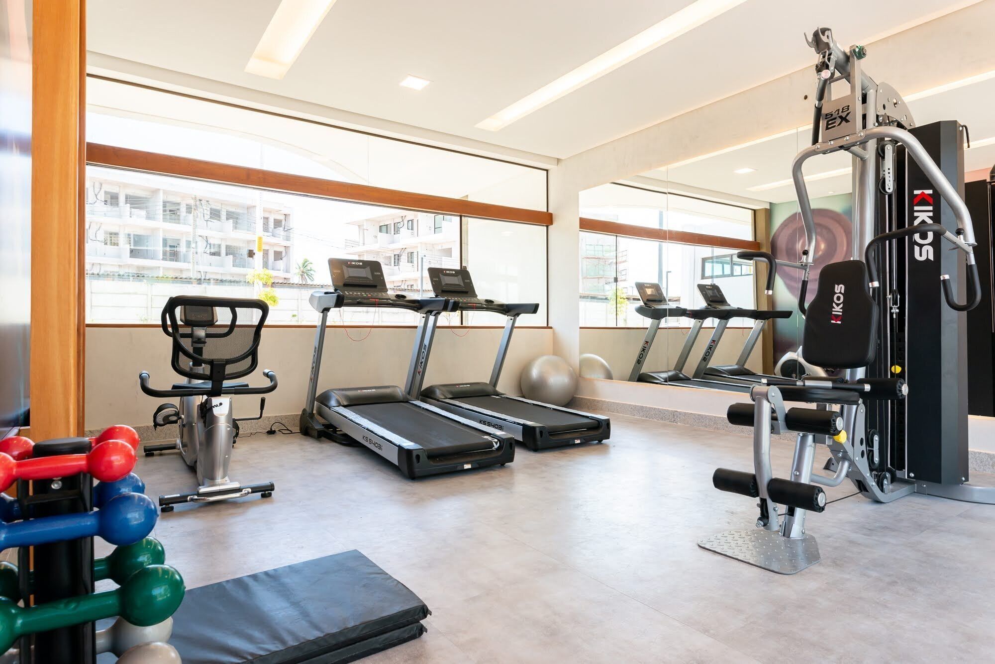 Un gimnasio con cintas de correr, una banca para pesas y pelotas de ejercicio.