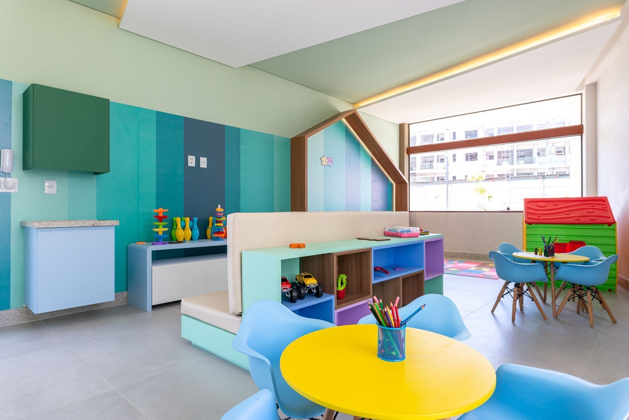 A children's playroom with a sofa, a table, and colorful chairs.