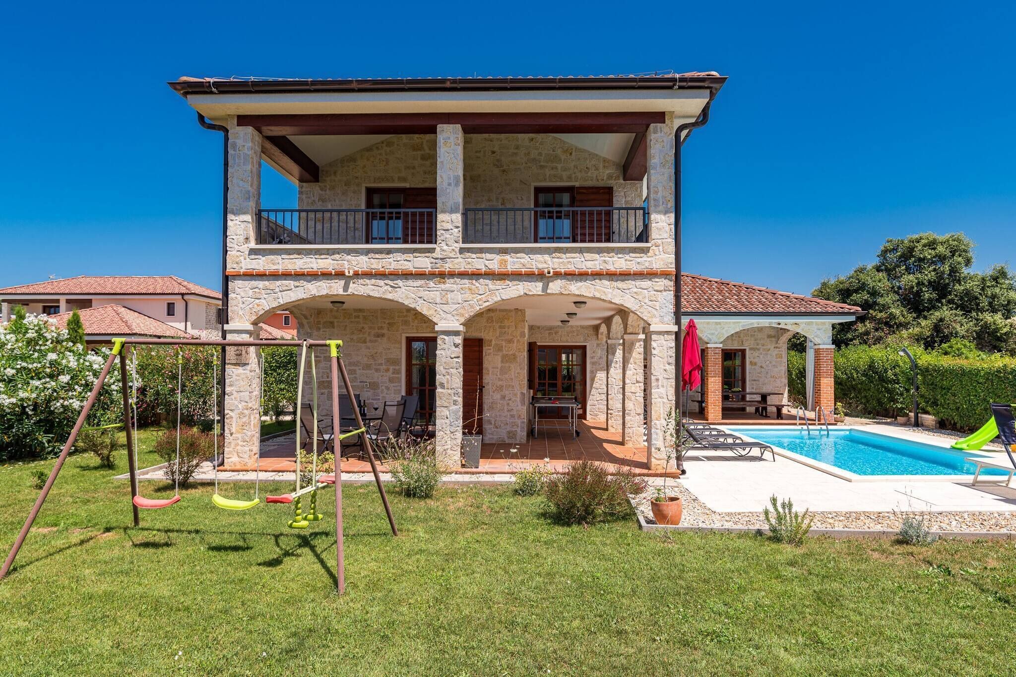 A two-story house with a swimming pool, a swing set, and a covered patio.