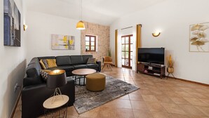 Una sala moderna con un sofá negro, una mesa de centro redonda y un televisor sobre un mueble de madera.