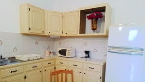 Une cuisine avec des meubles blancs, un four à micro-ondes, une machine à café et un réfrigérateur.