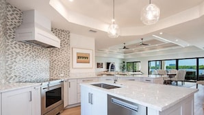 A modern kitchen with a large island, stainless steel appliances, and a view to the outdoors. - 5 Min Walk to Beach - Secluded Beachside Haven with Heated Pool, Water Toys, Privacy & (Bonita Springs)