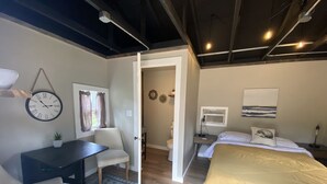 A bedroom with a bed, bedside table, lamp, and a clock on the wall.