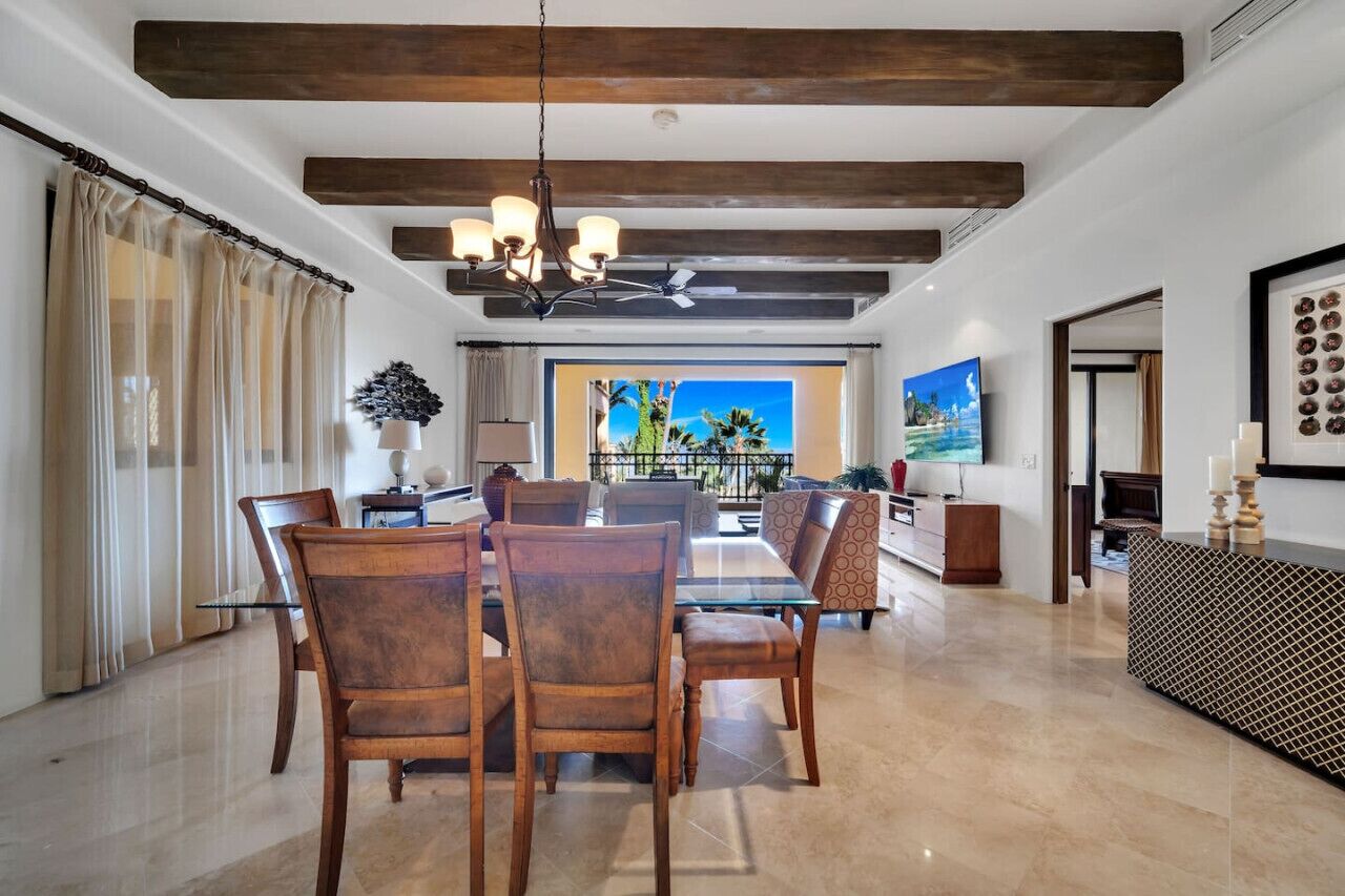 A spacious dining area with a modern chandelier, a large TV, and a view of the outdoors.