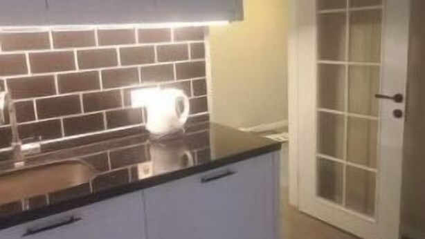 Eine Küche mit weißen Schränken, einer schwarzen Arbeitsplatte und einer gefliesten Rückwand.