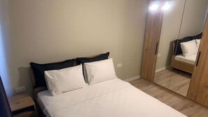Ein Schlafzimmer mit einem Bett, einem Nachttisch, einem Kleiderschrank und einem Spiegel.