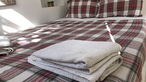 A neatly made bed with a plaid bedspread, two pillows, and a folded blanket. - Lisbon Cozy House w/Garden and Pool (Barcarena)