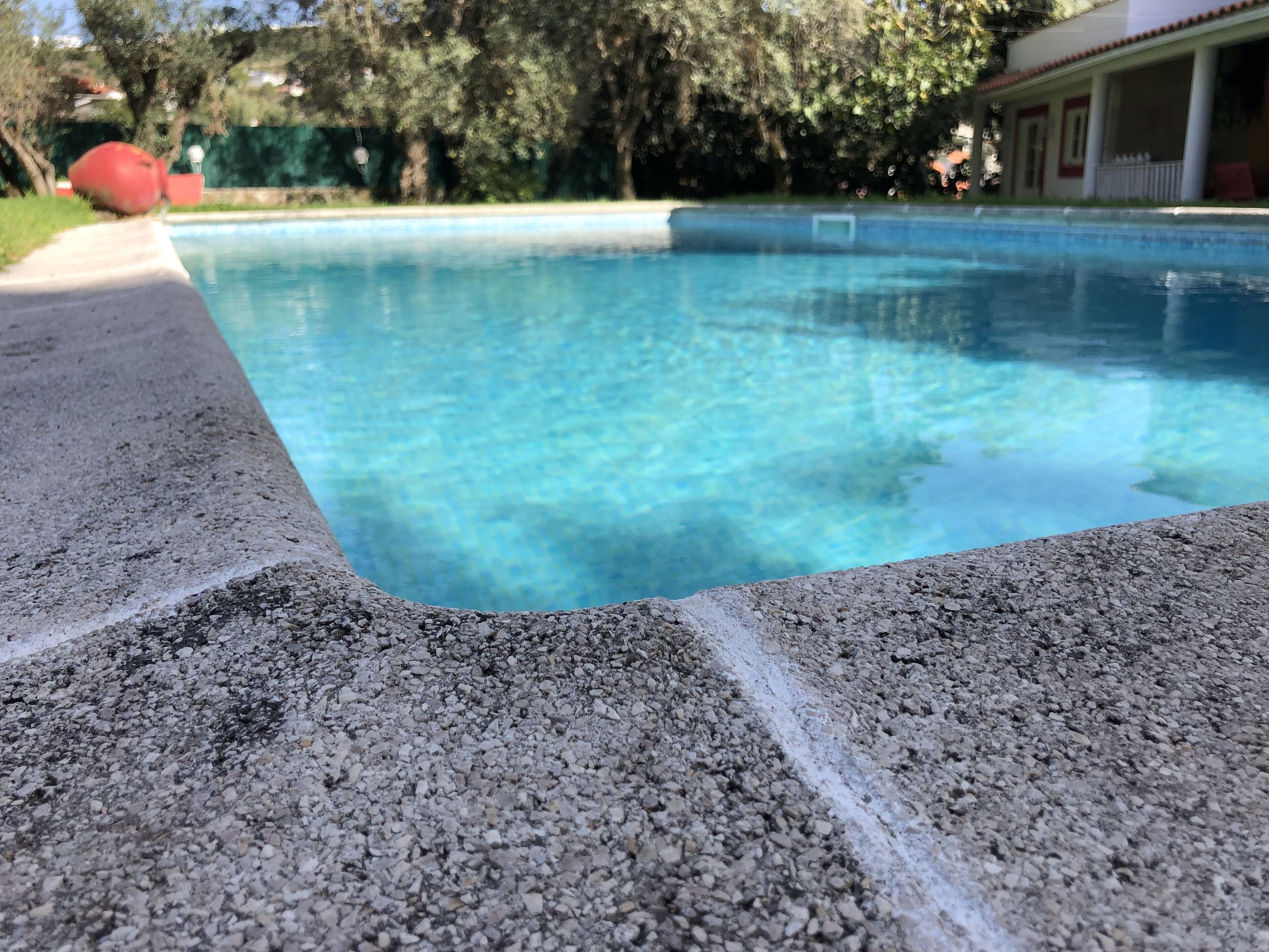 A swimming pool with clear blue water, surrounded by a pebble-textured edge.