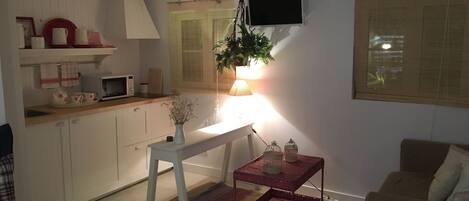 En kompakt opholdsstue med tekøkken, spiseplads og siddeområde.