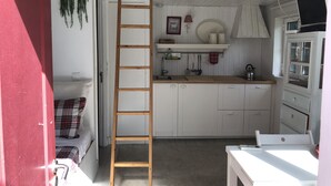 A compact kitchen with white cabinets, a wooden ladder, and a small dining area with a white table. - Lisbon Cozy House w/Garden and Pool (Barcarena)