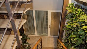 A staircase with metal railings leading to a room with a sliding glass door and a green plant wall.