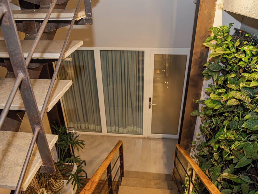 A staircase with metal railings leading to a room with a sliding glass door and a green plant wall.