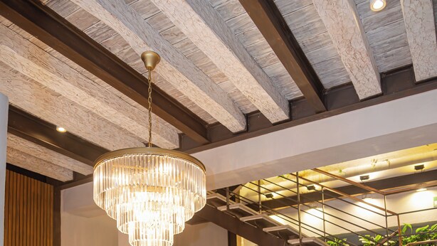 Een modern interieur met een trap, een kroonluchter en een bank met kussens.