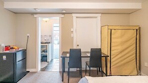Una habitación de hotel compacta con kitchenette, zona de comedor y cama.