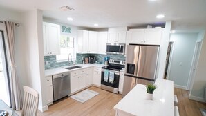Una cocina moderna con armarios blancos, electrodomésticos de acero inoxidable y un salpicadero de azulejos.