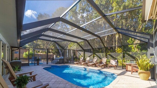 A covered outdoor swimming pool with lounge chairs and a pergola structure. - Sparkling pool and rejuvenating spa! (Saint Augustine)
