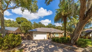 A residential property with a paved driveway, a garage, and a well-maintained lawn. - Sparkling pool and rejuvenating spa! (Saint Augustine)