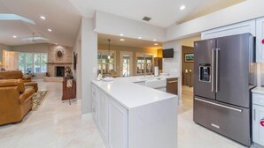 A spacious kitchen with a large island, stainless steel appliances, and a fireplace. - Sparkling pool and rejuvenating spa! (Saint Augustine)