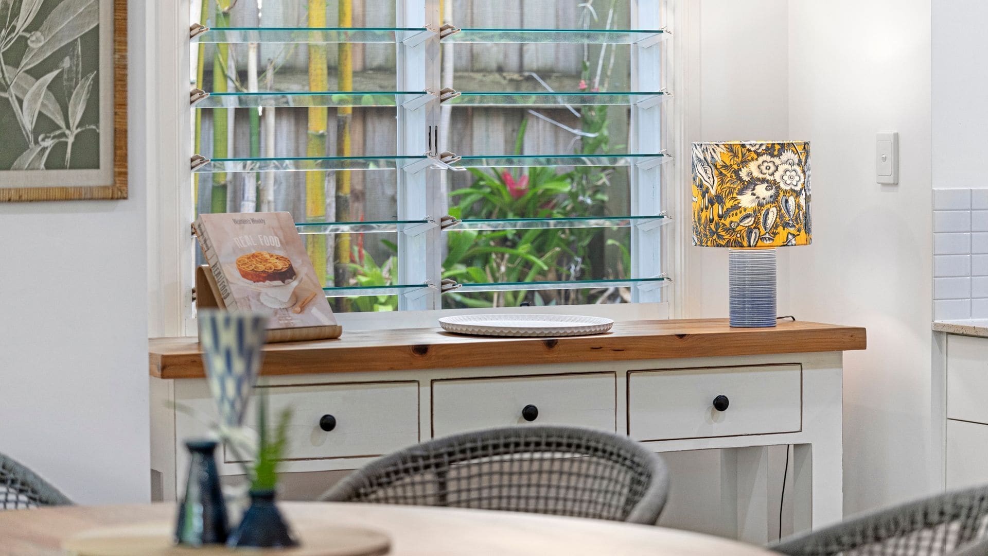 A kitchen with a window, a plate, a book, and a lamp.