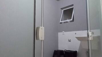 A room with a sliding glass door, a small window, a whiteboard, and two black trash bins.