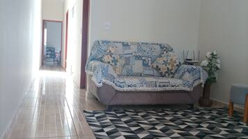 Una sala de estar con un sofá, un tapete estampado y una planta en maceta.