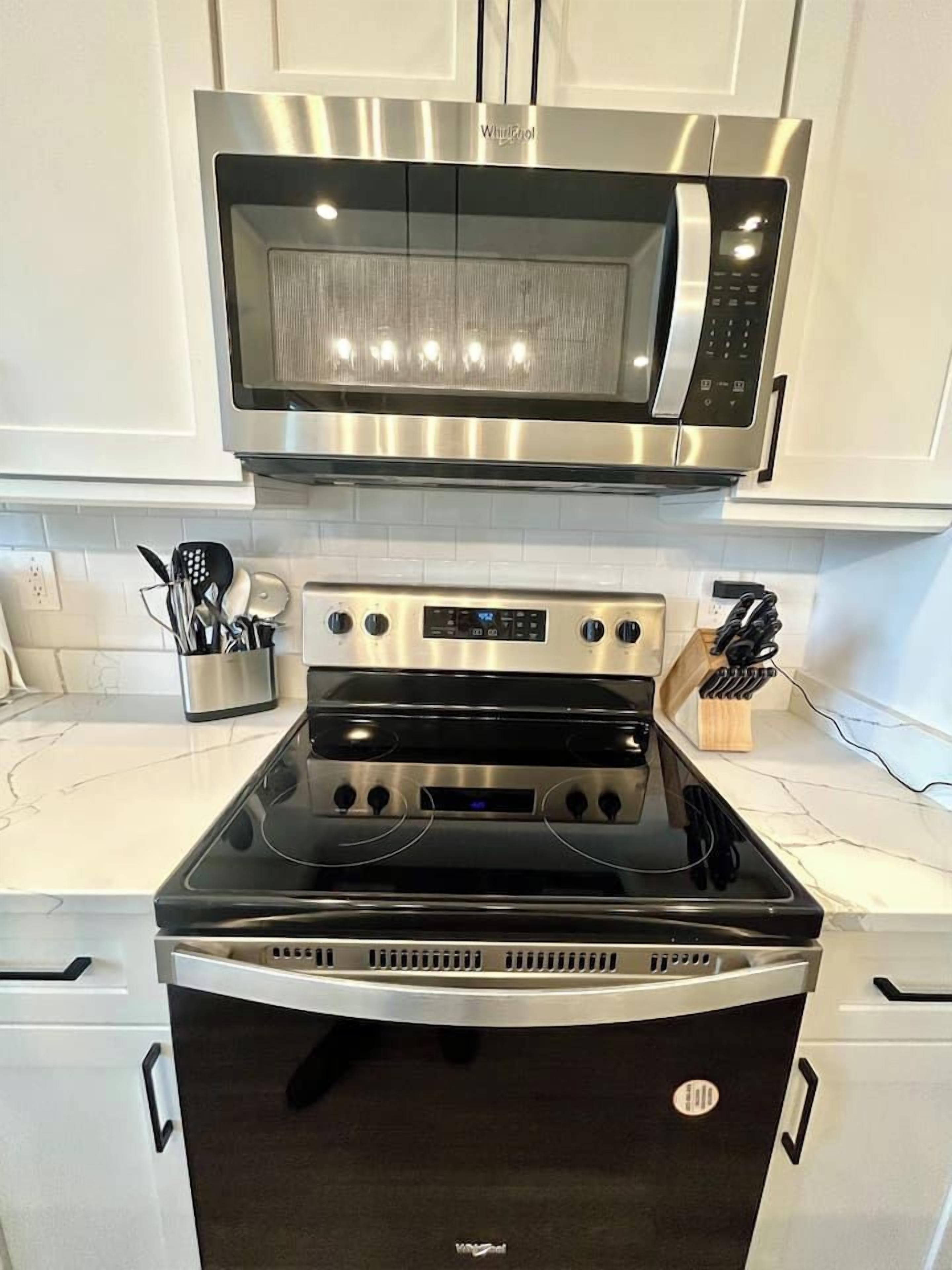 Una cocina con microondas de acero inoxidable, horno doble y lavavajillas.