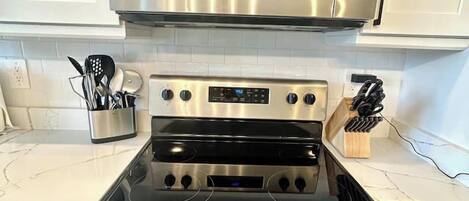 Una cocina con microondas de acero inoxidable, horno doble y lavavajillas.